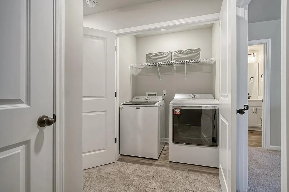 A tidy laundry area featuring a washing machine and dryer, with shelves holding storage bins above. The setup is organized and convenient, making everyday tasks easier for guests.