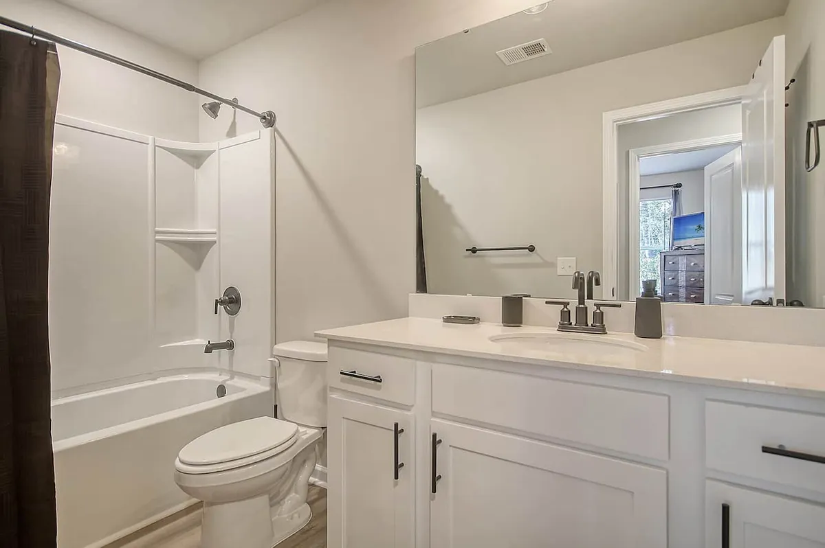 An inviting bathroom featuring a vanity sink, a mirror, and a relaxing bathtub. The space is designed for personal grooming and comfort, perfect for an evening soak or preparing for the day ahead.