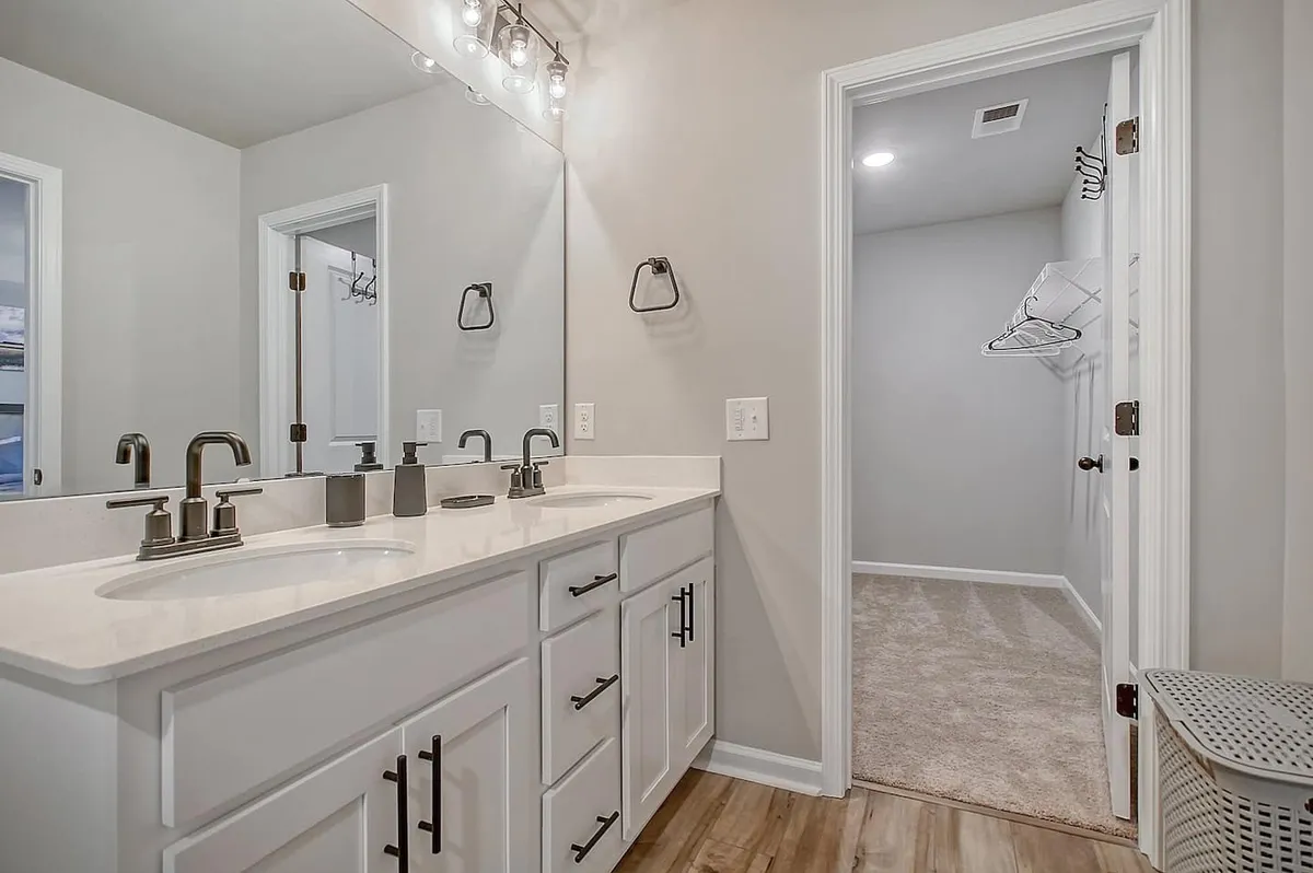 A modern bathroom with a double vanity, large mirrors, and elegant light fixtures. The space is clean and inviting, ready for morning routines or evening wind-downs, and offers ample room for personal care.