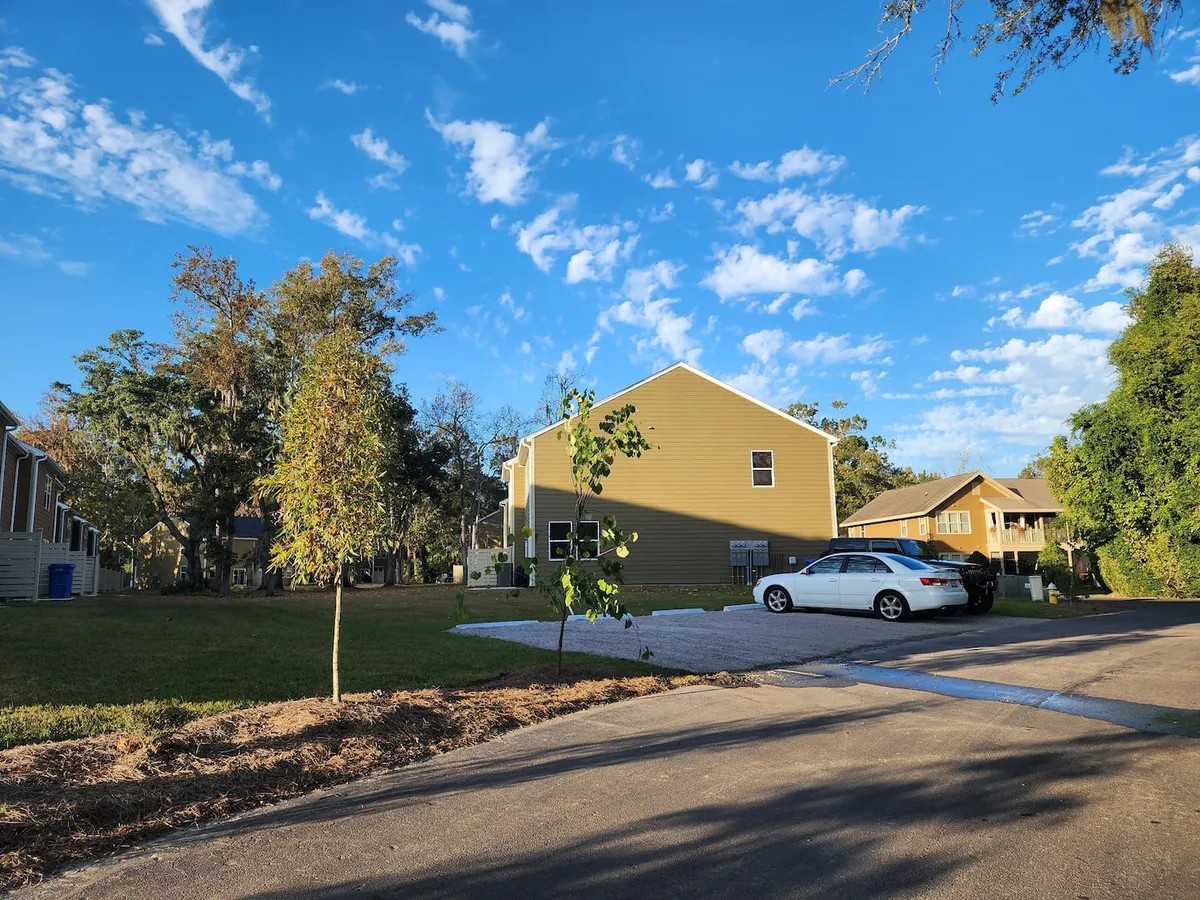 A friendly neighborhood streetscape with houses nestled among trees, driveways, and well-maintained front yards. The scene evokes a sense of community and calm, showcasing opportunities for outdoor gatherings and neighborhood walks.
